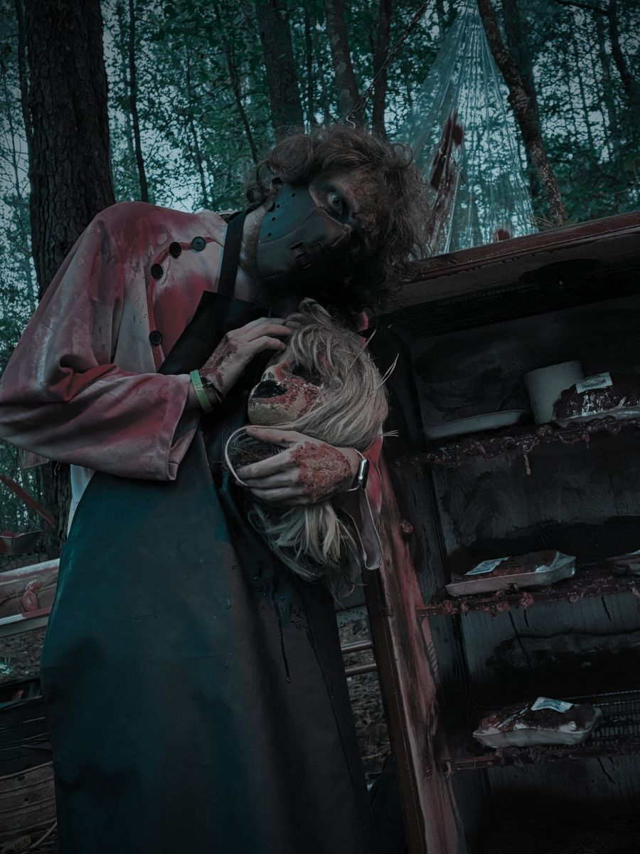 Bobby the Butcher: a figure in a blood-stained apron beside a rusted cabinet in the woods.
