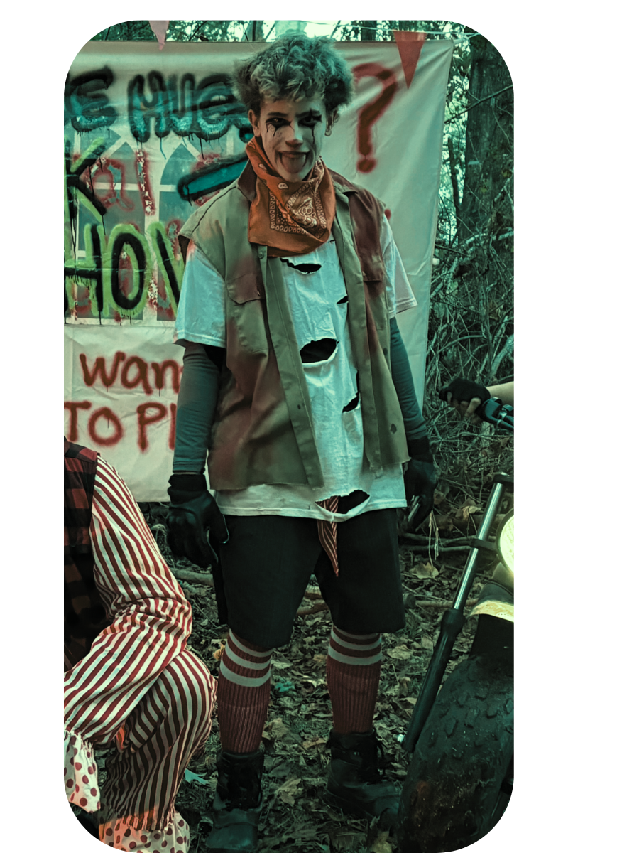 Trouble: a grinning youth in a ragged vest and bandana standing before a spray-painted sign.